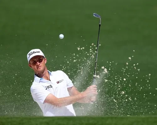 Professional golfer takes a bunker swing.
