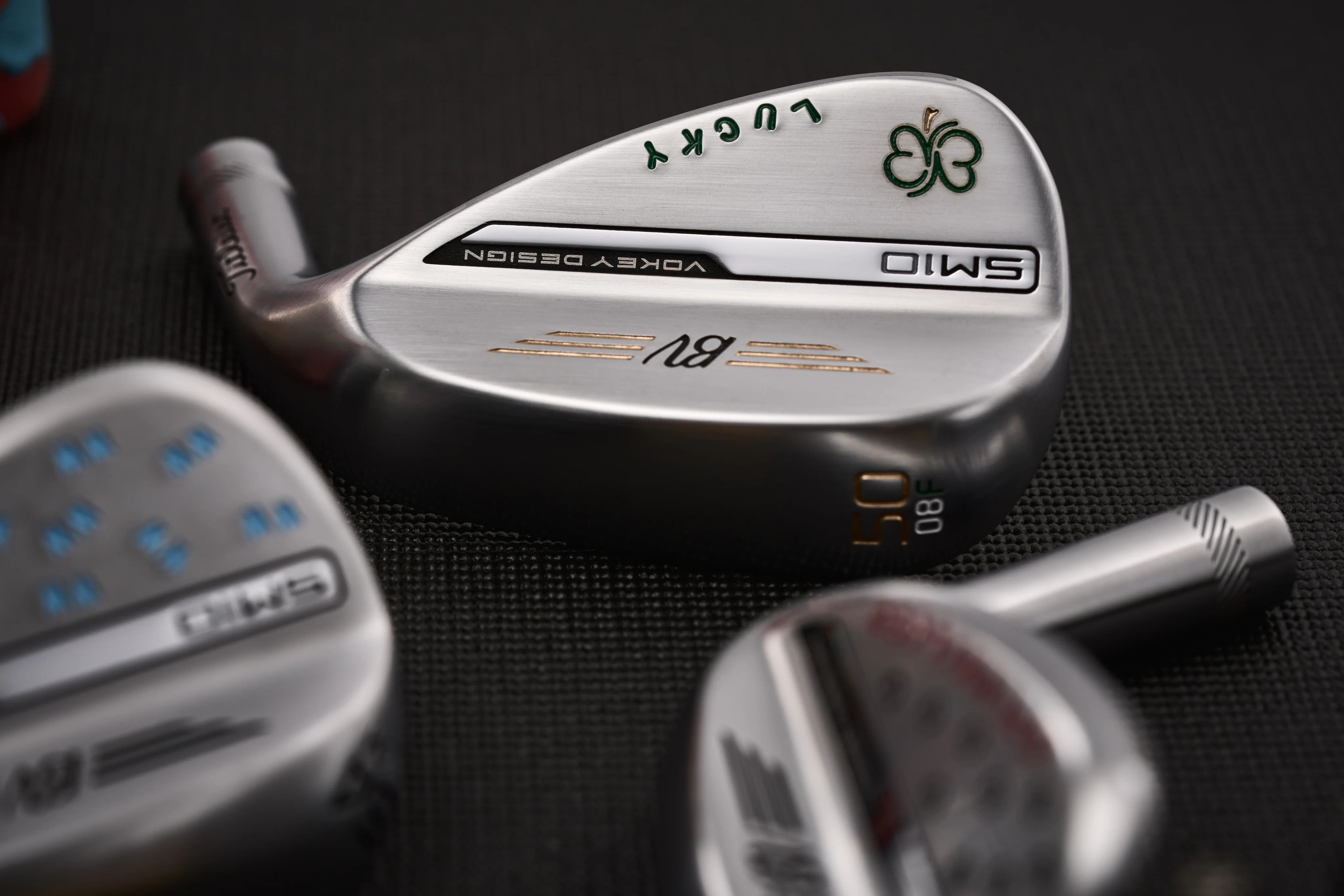An SM10 Vokey design iron with a green four leaf clover and the word, Lucky, engraved on the clubhead.